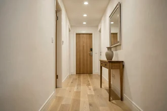 Couloir étroit et lumineux avec parquet en chêne, table console et miroir mural pour optimiser l'éclairage