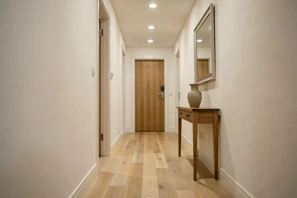 Couloir étroit et lumineux avec parquet en chêne, table console et miroir mural pour optimiser l'éclairage